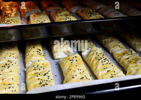 Rohe Phyllo-Brötchen, gefüllt mit Spinat, Käse oder Kartoffeln. Gebäck auf gebackenen Tablettenrollen verpackt. Der türkische Name ist kalem borek. Stockfoto