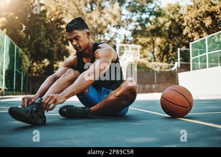 Basketballplatz, Mann und Schuhe bereiten sich auf das Training in der Freizeit- und Sportanlage vor. Sport-, Bewegungs- und Fitness-Mann mit Schnürband, der sich bereit macht Stockfoto