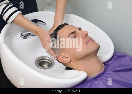 Professioneller Friseur wäscht die Haare des Klienten im Waschbecken, Schließung Stockfoto