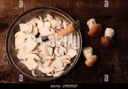 Messer, geschnittene und ganze Pilze auf Holztisch, flach verlegt Stockfoto