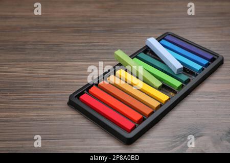 Farbenfrohe Pastelltöne im Tablett auf einem Holztisch, Platz für Text. Zeichenmaterialien Stockfoto