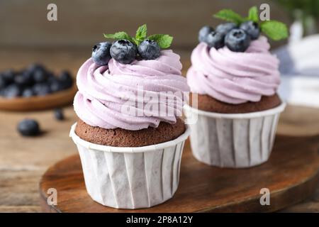 Süße Cupcakes mit frischen Blaubeeren auf Holzbrett, Nahaufnahme Stockfoto