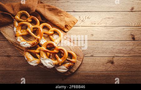 Frisch gebackene hausgemachte deutsche Brezel mit Meersalz auf einem Holztisch. Klassischer Biersnack, gebackenes Gebäck. Stockfoto