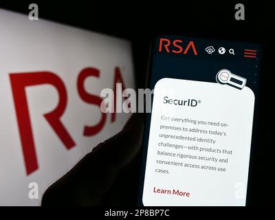 Person, die ein Mobiltelefon mit einer Webseite des US-Unternehmens RSA Security LLC auf dem Bildschirm vor dem Unternehmenslogo hält. Konzentrieren Sie sich auf die Mitte des Telefondisplays. Stockfoto