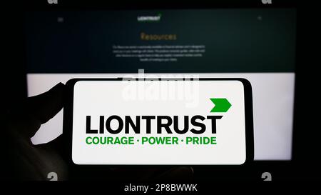 Person, die ein Smartphone mit dem Logo des britischen Unternehmens Liontrust Asset Management plc auf dem Bildschirm vor der Website hält. Konzentrieren Sie sich auf das Display des Telefons. Stockfoto