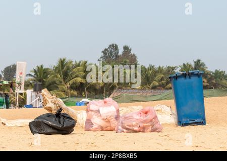 Candolim, Goa, Indien - Januar 2023: Ein Mülleimer und Plastiktüten voller Müll am Strand in Sinquerim. Stockfoto