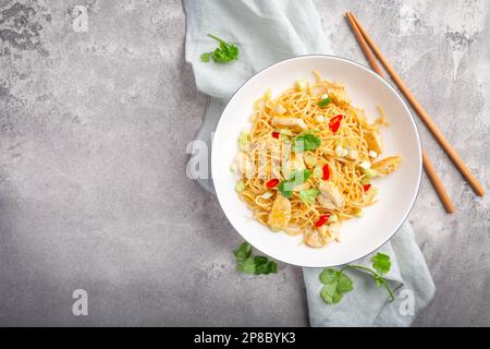 Gebratene Nudeln mit Hähnchen und Gemüse in eine weiße Schüssel rühren. Asiatisches Essen. Stockfoto