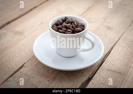 Kaffeetasse mit gerösteten Bohnen auf Holzhintergrund Stockfoto