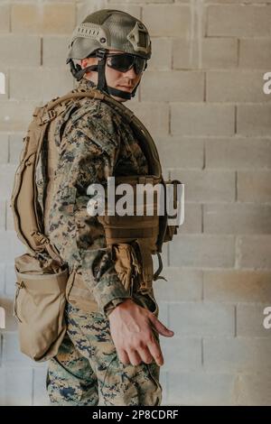 Ein Soldat in Uniform steht vor einer Steinmauer in voller Kriegsausrüstung und bereitet sich auf die Schlacht vor Stockfoto