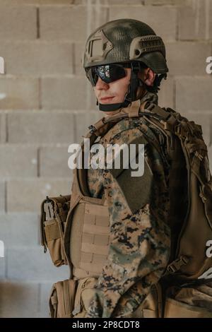 Ein Soldat in Uniform steht vor einer Steinmauer in voller Kriegsausrüstung und bereitet sich auf die Schlacht vor Stockfoto