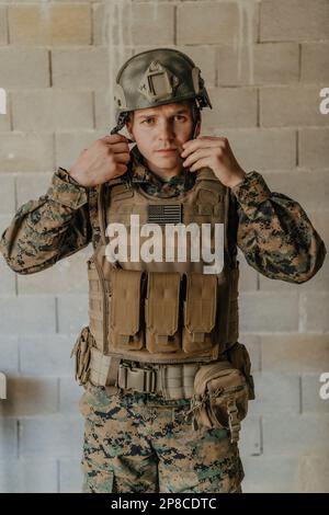 Ein Soldat in Uniform steht vor einer Steinmauer in voller Kriegsausrüstung und bereitet sich auf die Schlacht vor Stockfoto