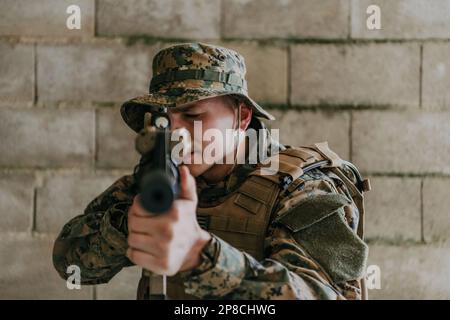 Ein Soldat in Uniform steht vor einer Steinmauer in voller Kriegsausrüstung und bereitet sich auf die Schlacht vor Stockfoto