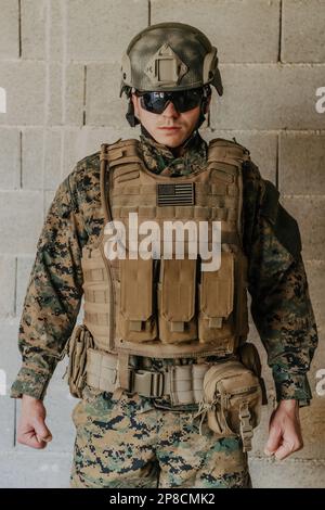 Ein Soldat in Uniform steht vor einer Steinmauer in voller Kriegsausrüstung und bereitet sich auf die Schlacht vor Stockfoto