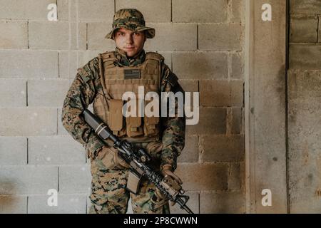 Ein Soldat in Uniform steht vor einer Steinmauer in voller Kriegsausrüstung und bereitet sich auf die Schlacht vor Stockfoto