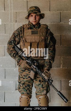 Ein Soldat in Uniform steht vor einer Steinmauer in voller Kriegsausrüstung und bereitet sich auf die Schlacht vor Stockfoto