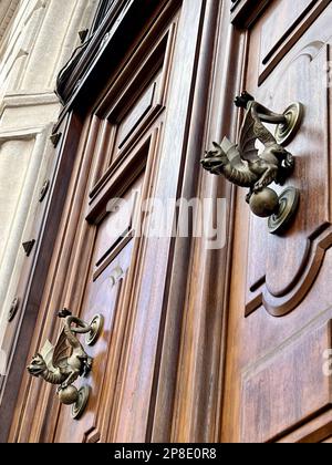 Tür, Holztür mit Drachenförmigen Türknöpfen oder Klopfen. Eingang eines Gebäudes. Türknöpfe oder Griffe wie Drachen Stockfoto