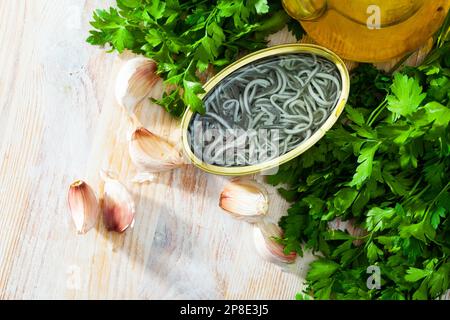 Eingelegte Aale in offener Dose mit Knoblauch am Tisch Stockfoto