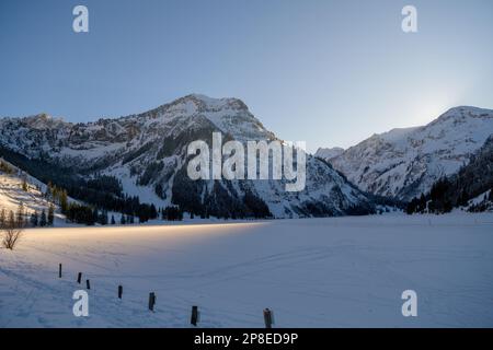 Letzter Sonnenstrahl bei Sonnenuntergang über dem gefrorenen See in den alpen Stockfoto