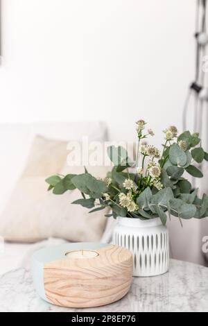 Nahaufnahme einer Vase mit Blumen und Kerzen auf einem Tisch im Wohnzimmer Stockfoto