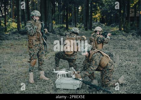 Modern Warfare Soldiers Squad verwenden Drohne für Scouting und Überwachung während der militärischen Operation im Wald. Stockfoto