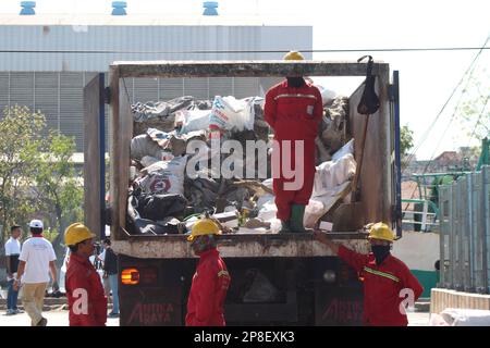 Reinigungskräfte in Uniform sammeln Müll in einem Müllwagen im Hafenbereich Stockfoto