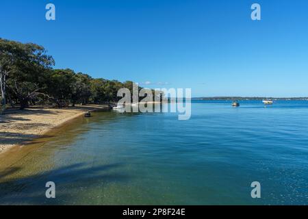 Blick von der Anlegestelle auf Coochiemudlo Island über das ruhige blaue Wasser der Moreton Bay nach Macleay Island und Stradbroke Island in der Ferne. Stockfoto