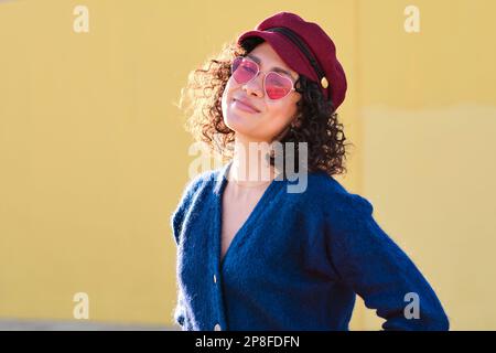 Süße Frau mit Hut und Sonnenbrille, die in die Kamera schaut Stockfoto