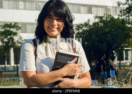 Porträt einer jungen venezolanischen Frau mit kurzen Haaren und weißer Freizeitkleidung, mit der Taille nach oben, draußen stehend, in die Kamera schauend und ihre Universen liebte Stockfoto