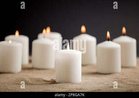 Kerzen mit brennender Flamme, im Sand Stockfoto