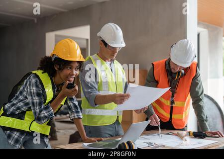 Architektin mit Walkie-Talkie und Bauingenieur, die zusammen an der Baustelle das Bauprojekt inspizieren Stockfoto