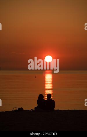 Silhouette eines Paares vor dem Sonnenuntergang am Strand Stockfoto