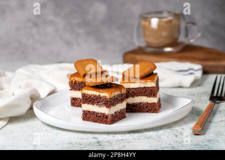 Kleine Dessertkuchen. Karamell Petit 4 auf einem weißen Teller mit dunklem Hintergrund. Keks, französischer Petit, vier Kuchen Stockfoto