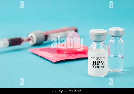 Arzneimittelfläschchen Humanes Papillomvirus : HPV-Impfstoff und Kondom mit Blutprobe für den Test in Blutröhrchen. Stockfoto