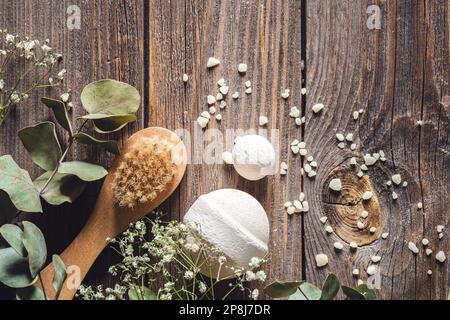 Bürste, Badebomben, Meersalz und getrocknete Blumen auf Holzhintergrund. Stockfoto