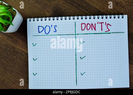Konzept von "do's and Don't's" schreiben Sie auf ein Buch isoliert auf einem Holztisch. Stockfoto