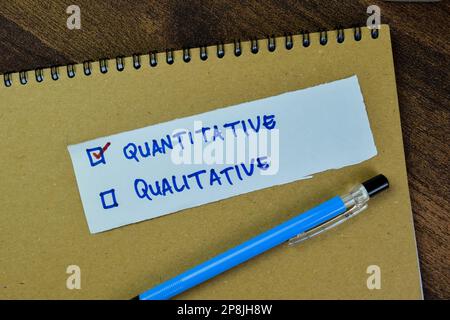 Konzept der quantitativen und qualitativen Schreibweise auf auf Holztisch isolierten Haftnotizen. Stockfoto