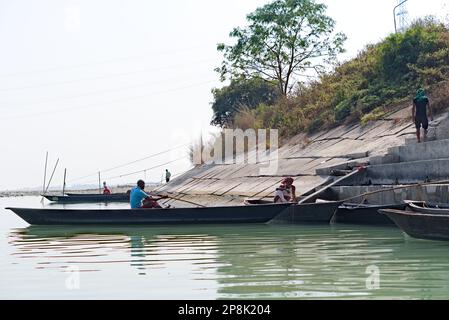 Bootsfahrer sitzen auf einem Holzboot am Flussufer Stockfoto