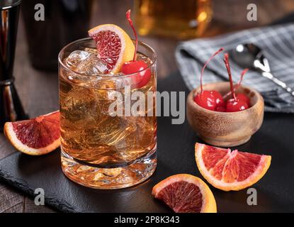 Altmodischer Whiskey-Cocktail mit Kirsch- und Orangenscheiben auf rustikalem Holzhintergrund Stockfoto