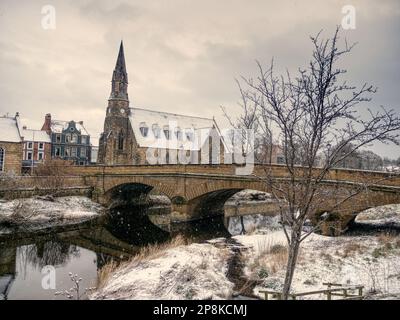 Im Winter bietet sich ein verschneiter Blick auf die St. George's Church entlang der Telford Bridge mit ihren Bögen über den Fluss Wansbeck in Morpeth, Northumberland Stockfoto