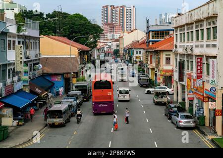 Die Leute stürzen sich durch den Verkehr und überqueren die Straße auf die andere Seite in Geylang, Singapur. Editorial Stockfoto