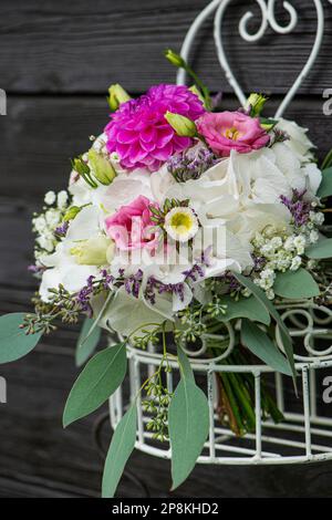 Sommerblumenstrauß mit Rosen in einem Metallkorb Stockfoto
