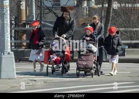 Die Kinder eines chassidischen jüdischen Paares feiern Purim in Kostümen. Auf der Lee Avenue in Williamsburg, Brooklyn, New York. Stockfoto