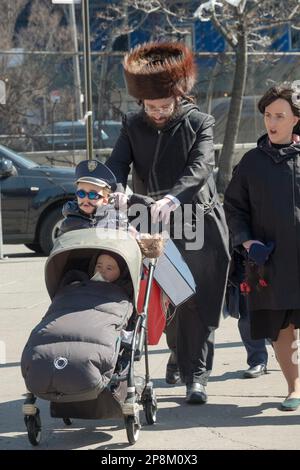 Eine orthodoxe jüdische Familie feiert Purim, den Vater mit seinem streimeligen Pelzhut und den Sohn mit einem Kostüm. In Brooklyn, New York. Stockfoto