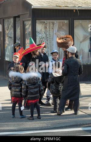 Zwei orthodoxe jüdische Familien treffen sich auf Purim, einem Feiertag, an dem traditionell Shtreimel-Pelzhüte und -Kostüme getragen werden. In Brooklyn, New York City. Stockfoto