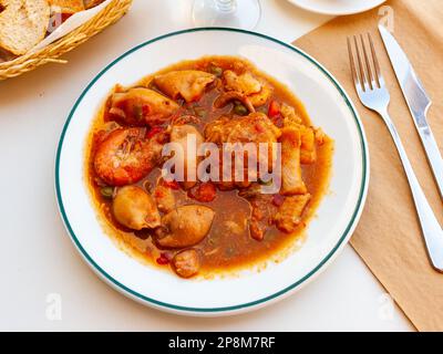 Nahaufnahme der traditionellen spanischen Zarzuela auf weißem Teller auf weißer Tischdecke Stockfoto