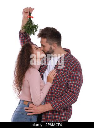 Ein glückliches Paar küsst sich unter Mistelzweigen auf weißem Hintergrund Stockfoto