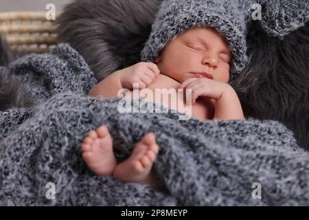 Ein bezauberndes Neugeborenes, das im Korb mit Kunstfell liegt Stockfoto