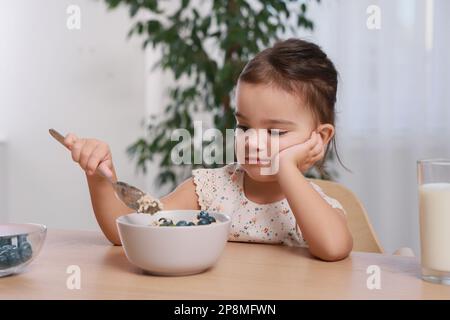 Süßes kleines Mädchen weigert sich, zu Hause zu frühstücken Stockfoto