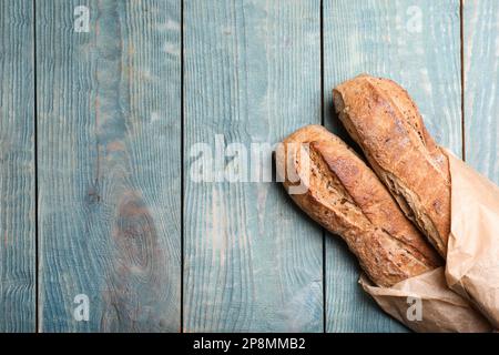 Leckere Buchweizen-Baguettes im Paket auf hellblauem Holztisch, Draufsicht. Platz für Text Stockfoto