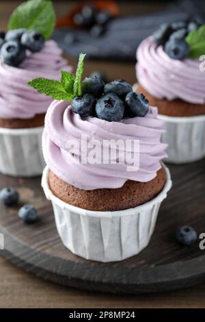 Süßer Cupcake mit frischen Blaubeeren auf Holzbrett, Nahaufnahme Stockfoto